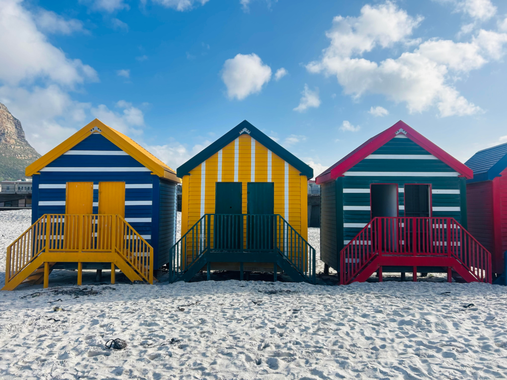 Three striped coloured beach huts at Muizenberg beach, Cape Town