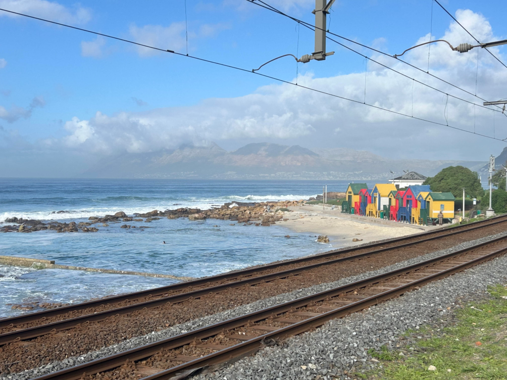 Colourful beach huts in front of train lines at St James Beach on a Cape Peninsula day trip